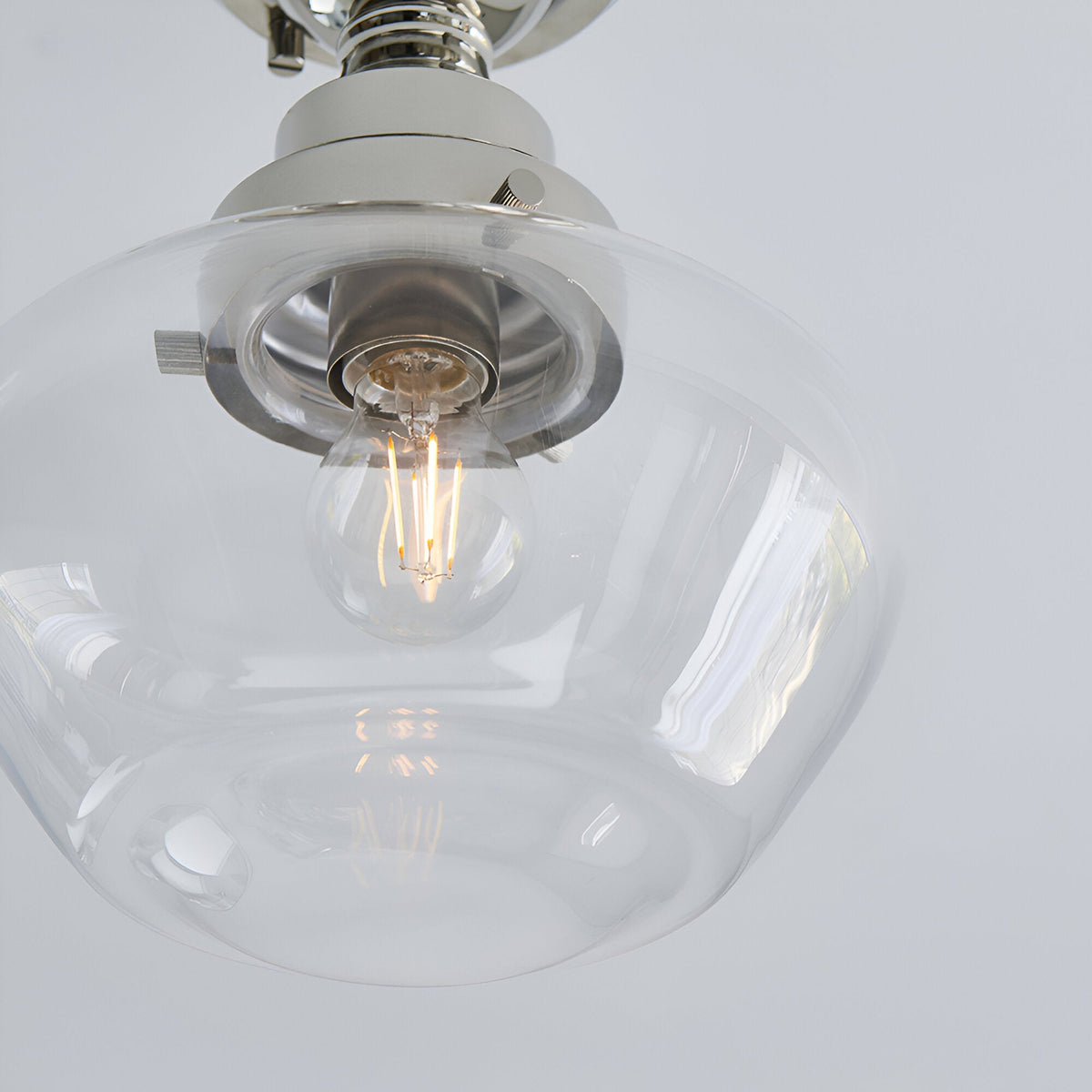 Close-up of the Endon Kedleston semi-flush ceiling light showing its clear glass shade, exposed E27 filament bulb, and polished nickel mount.