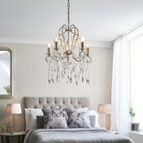 Endon Aldwood 5 light pendant in aged silver with cut crystal droplets, hanging above a grey upholstered bed between two lamps in a bedroom.
