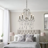 Endon Aldwood 5 light pendant in aged silver with faceted crystal droplets, hung above an upholstered bed with pink shaded lamps in a neutral bedroom.