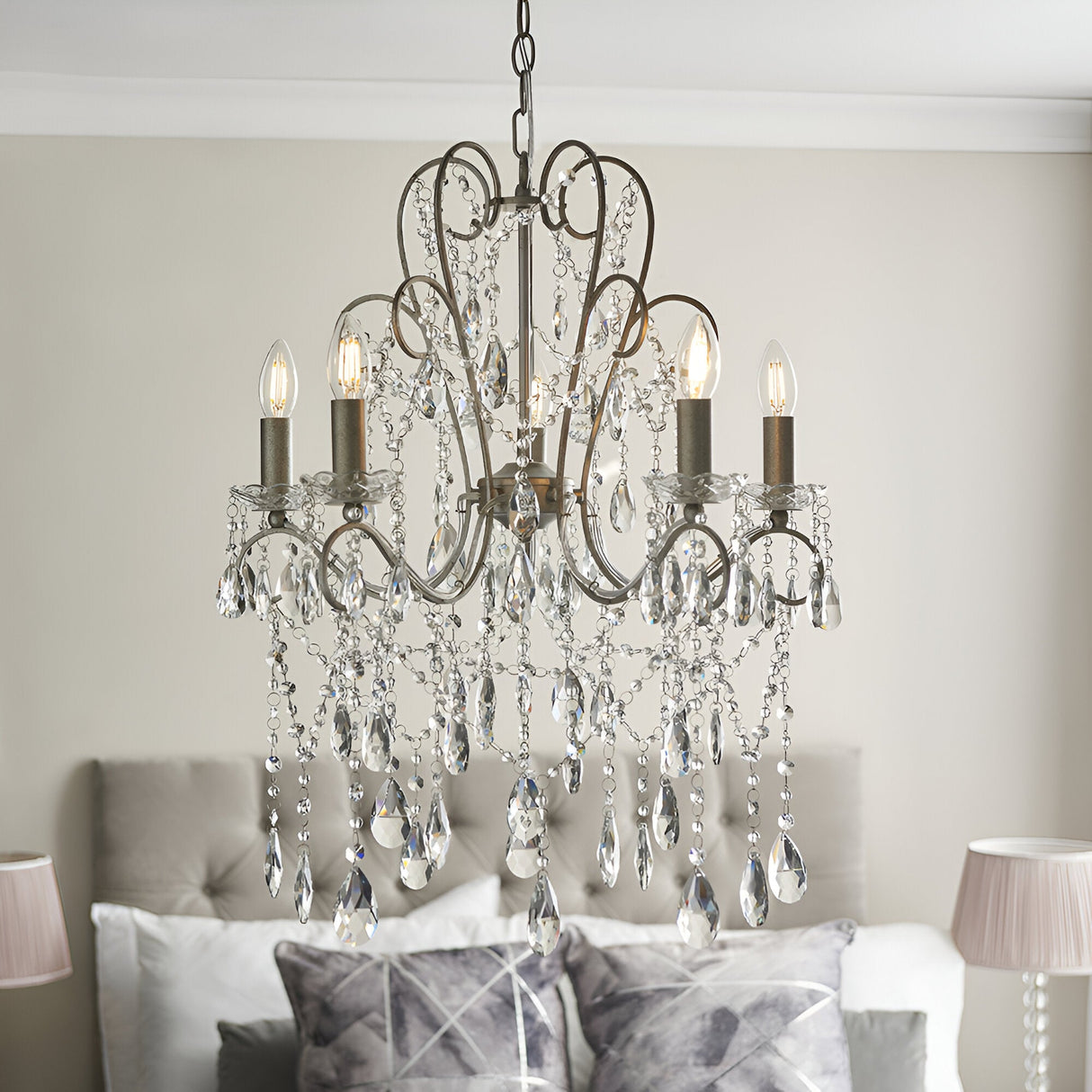 Endon Aldwood 5 light pendant in aged silver with scrolled metal frame and cascading faceted crystal drops, shown above a bed in a neutral bedroom.