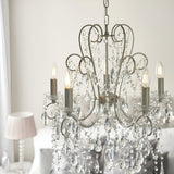 Endon Aldwood 5 light pendant in aged silver with scrolled metalwork and faceted crystal drops, hung above a bed in a soft neutral bedroom.