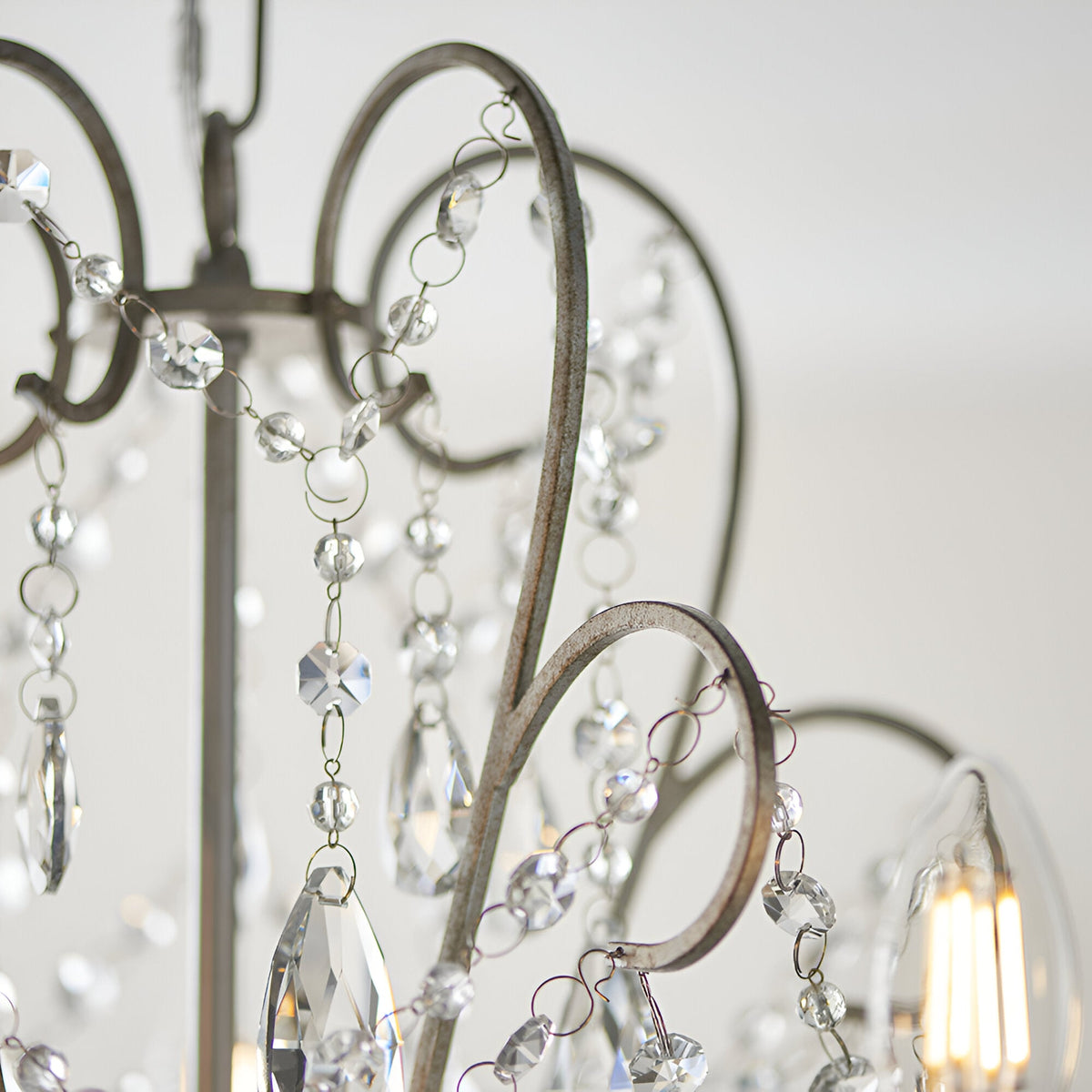 Close-up of Endon Aldwood 5 light pendant showing aged silver scrolled metalwork strung with clear faceted cut crystal beads and drops.