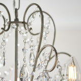 Close-up of Endon Aldwood 5 light pendant showing aged silver scrolled metalwork strung with clear faceted cut crystal beads and drops.