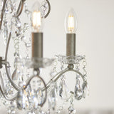 Close-up of Endon Aldwood 5 light pendant showing aged silver arms, cut crystal droplets, glass bobeches and lit E14 candle bulbs.