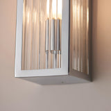 Close-up of Endon Castcombe bathroom wall light showing chrome-plated rectangular body and ribbed clear glass diffuser illuminated on a neutral wall.