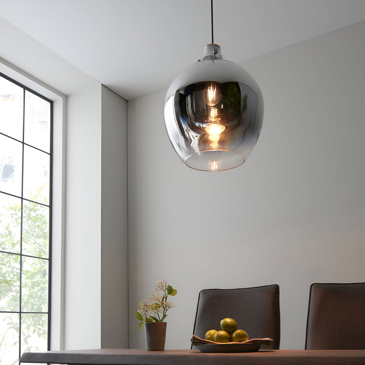 Castworth Glass Pendant in chrome, single E27 globe shade with ombre finish, hanging above a dining table in a bright neutral-toned room.