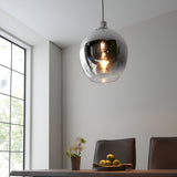 Castworth Glass Pendant in chrome, single E27 globe shade with ombre finish, hanging above a dining table in a bright neutral-toned room.