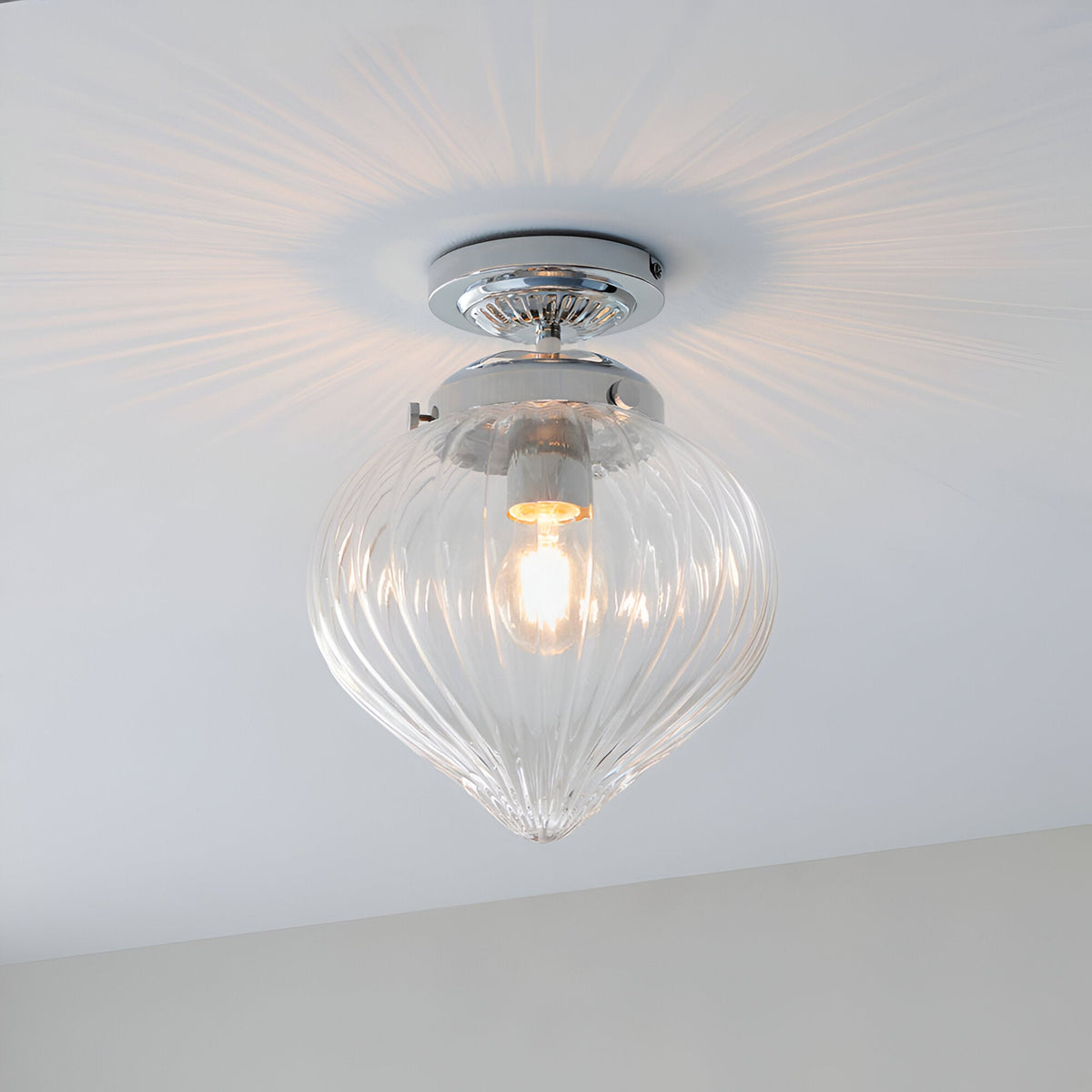 Endon Thornton flush bathroom ceiling light in chrome with a ribbed clear glass teardrop shade, shown illuminated against a white ceiling.