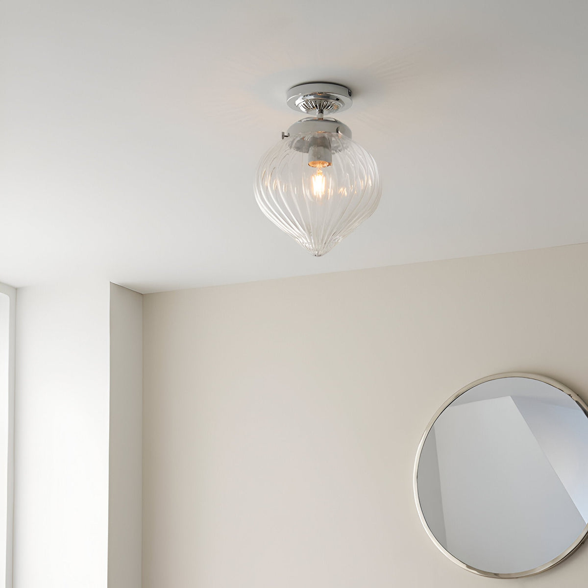 Endon Thornton flush bathroom ceiling light in chrome with a ribbed clear glass teardrop shade, installed on a white ceiling above a round mirror.