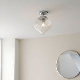 Endon Thornton flush bathroom ceiling light in chrome with a ribbed clear glass teardrop shade, installed on a white ceiling above a round mirror.