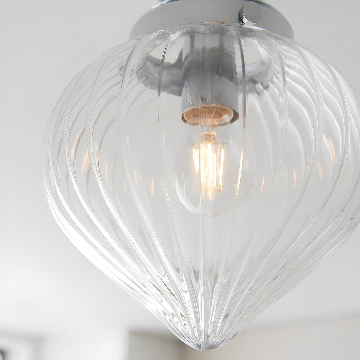 Close-up of the Endon Thornton flush bathroom ceiling light in chrome, with a ribbed clear glass teardrop shade and a lit E27 filament lamp.