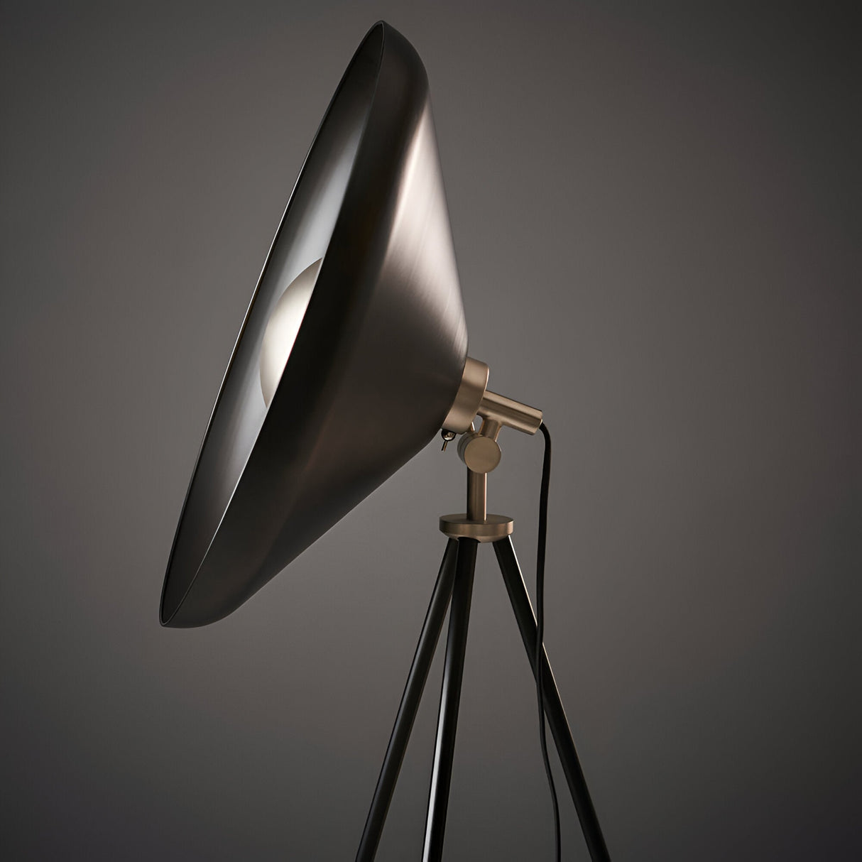 Endon Bramshaw floor lamp with a large tilted matt black conical shade, brushed nickel joint, and black tripod stand against a grey background.