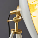 Close-up of Endon Bramshaw floor lamp showing brushed brass tilt joint, toggle detail, white shade edge and lit E27 filament bulb against a grey background.