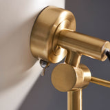 Close-up of the Endon Bramshaw Floor Lamp's brushed brass tilt joint and cylindrical head against a white shade and grey background.