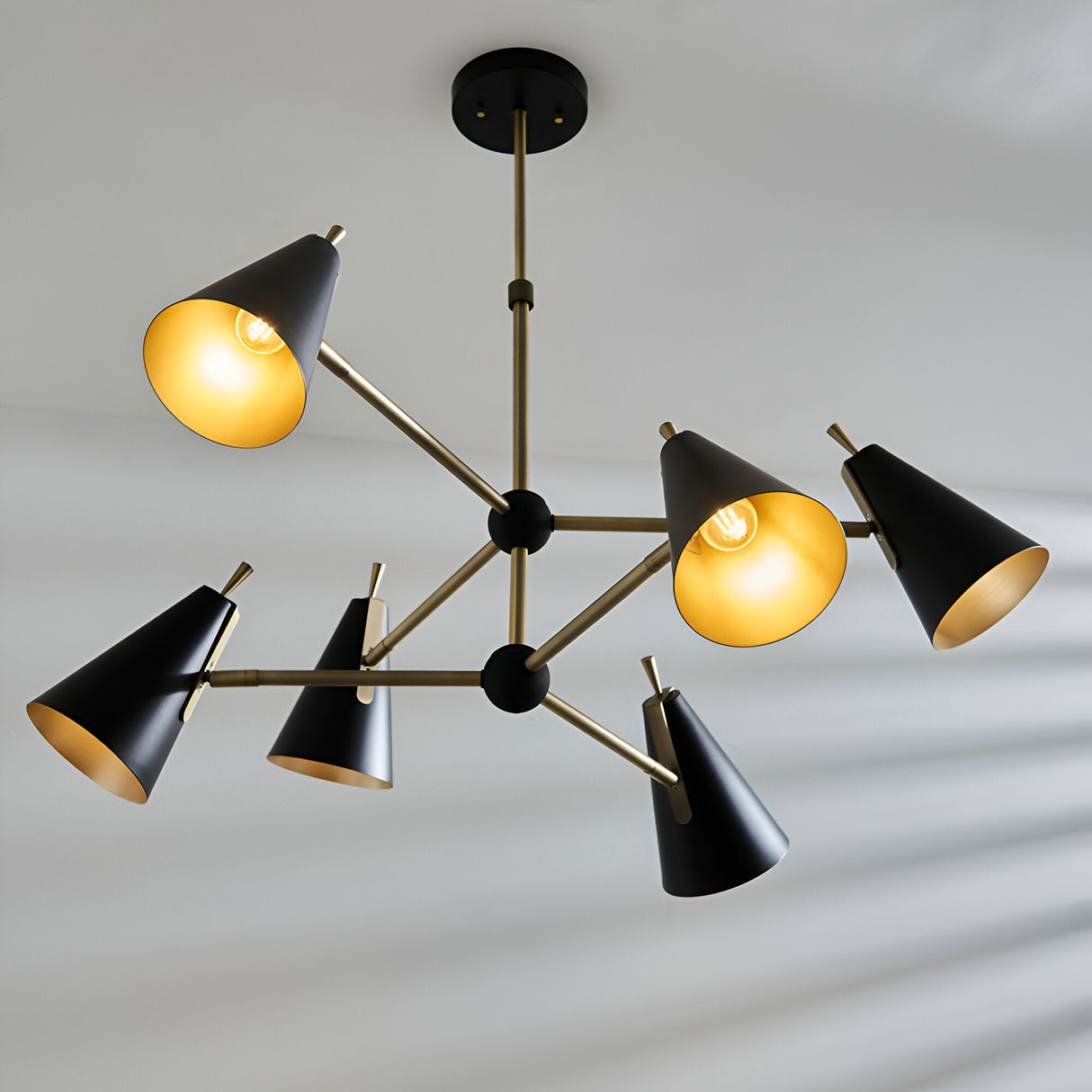Brackwick 6-light pendant featuring matt black cone shades, antique brass arms, a telescopic stem, and adjustable outward-angled heads.