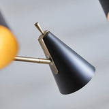 Close-up of the Brackwick 6 Light Pendant's matt black cone shade on a brass arm with adjustable tilt joint, shown against a soft grey background.
