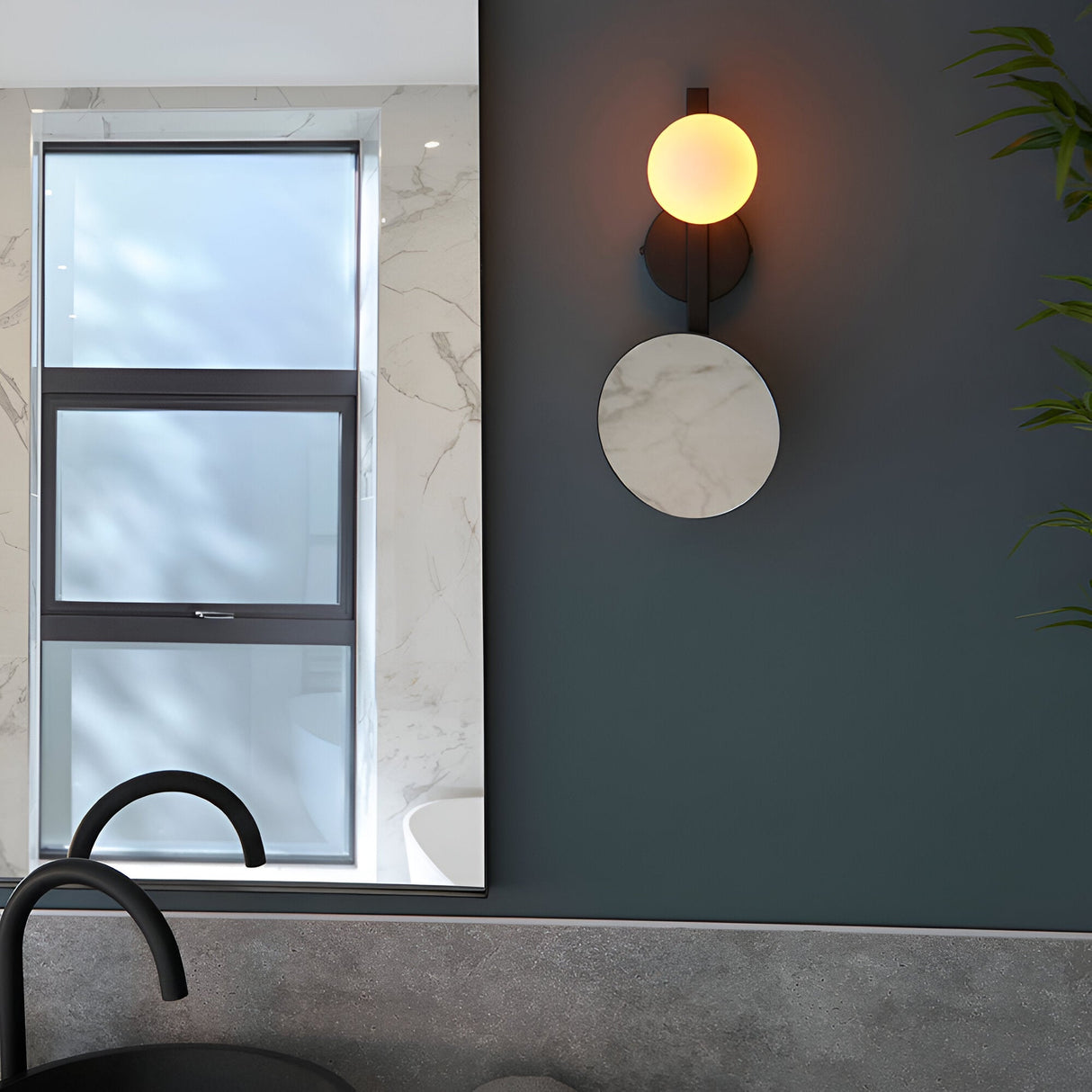 Endon Cliffshaw matt black bathroom wall light with opal glass sphere and round magnifying mirror, mounted on a dark wall beside a marble-framed window.