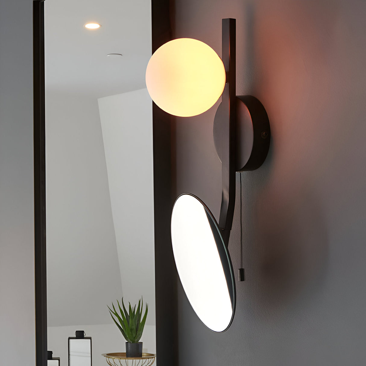 Endon Cliffshaw matt black bathroom wall light with an opal glass sphere and adjustable magnifying mirror, mounted beside a tall mirror.