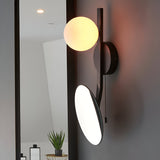 Endon Cliffshaw matt black bathroom wall light with an opal glass sphere and adjustable magnifying mirror, mounted beside a tall mirror.