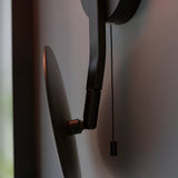 Close-up of the Endon Cliffshaw matt black bathroom wall light showing the adjustable mirror arm joints and pull cord switch against a pale wall.