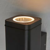 Close-up of the Carlford 2 Light Outdoor Wall Light in black aluminium, showing the square top with GU10 bulb and clear glass diffuser mounted on a grey wall.