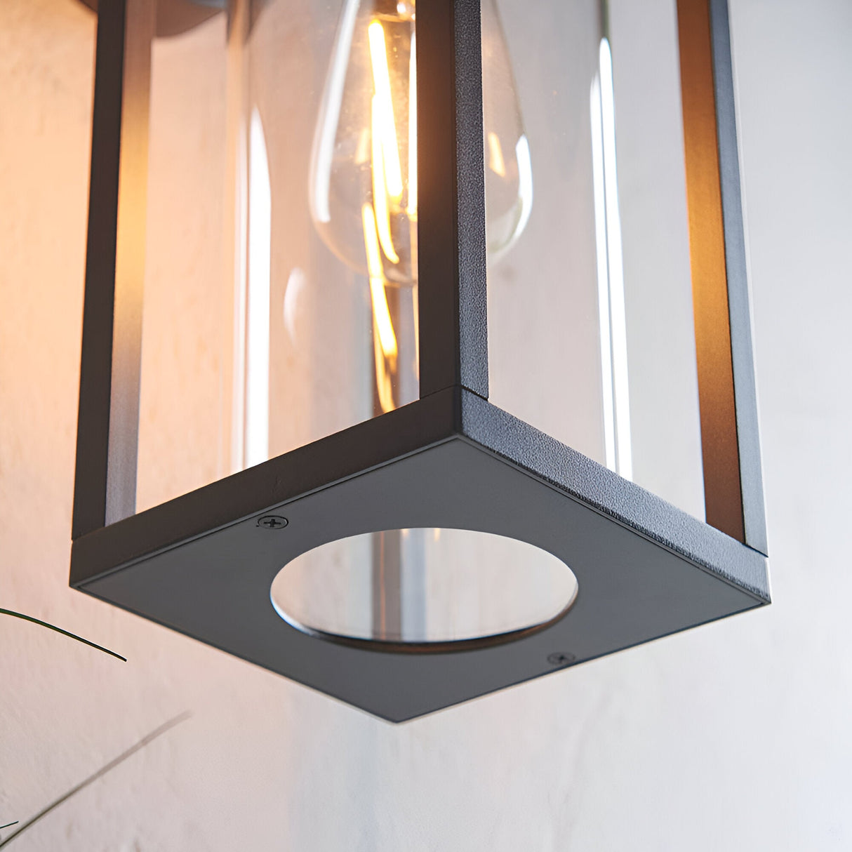 Close-up of the Endon Bramwood outdoor wall light base in textured black aluminium with clear glass panels and a warm filament E27 bulb.