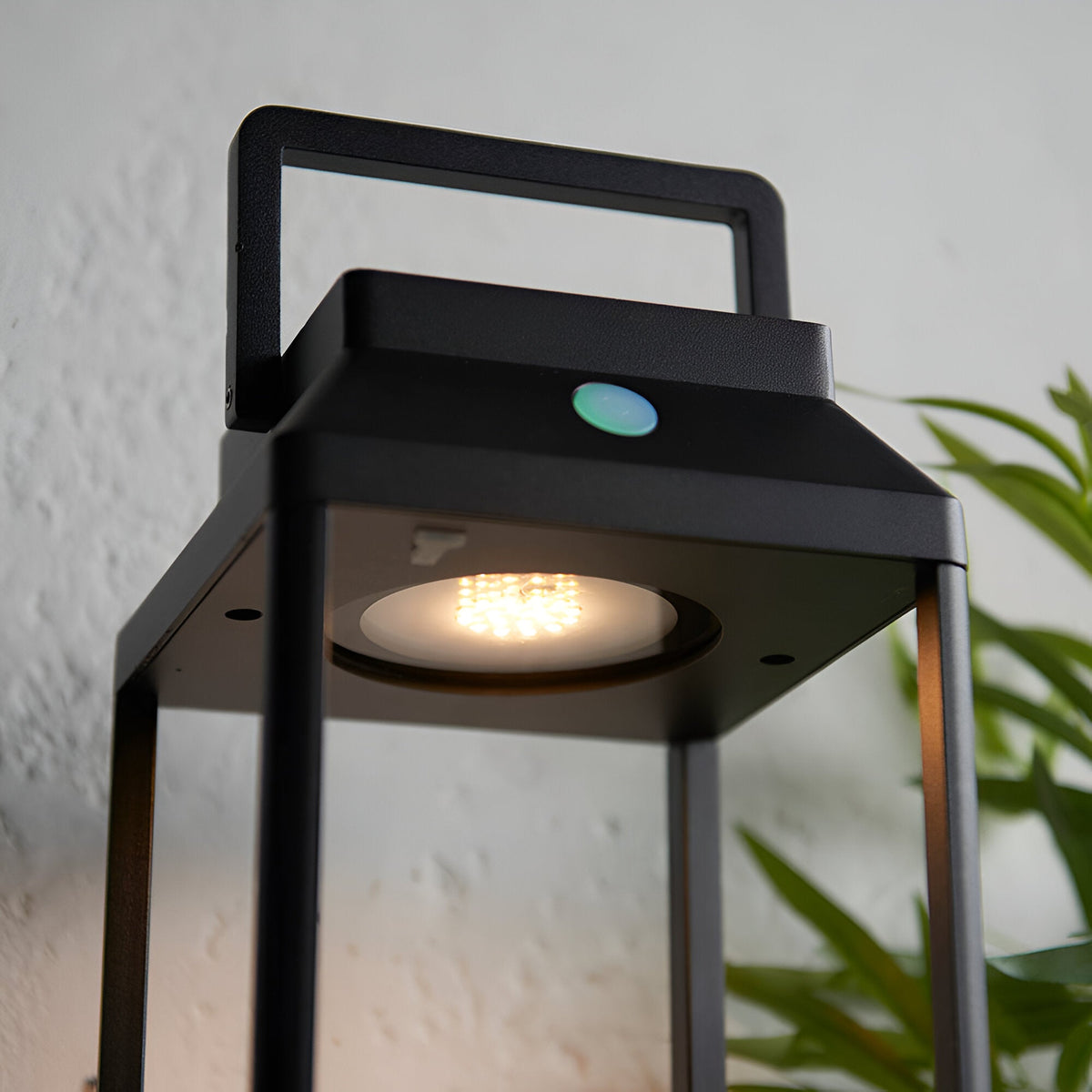 Caldshaw LED Solar Table Lamp in black, close-up of the lantern-style aluminium frame with warm white LED, touch dimmer button, and carry handle.