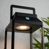 Caldshaw LED Solar Table Lamp in black, close-up of the lantern-style aluminium frame with warm white LED, touch dimmer button, and carry handle.