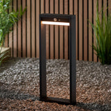 Endon Blythe LED solar post light in matte black aluminium with warm white diffuser and PIR sensor, on gravel beside a slatted wood fence and grasses.