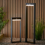 Two Endon Blythe LED solar post lights in black aluminium, tall and short rectangular frames with PIR sensors, set on gravel against a wood slat wall.