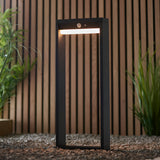 Endon Blythe LED solar post light in black aluminium with white diffuser and PIR sensor, set on gravel against a slatted wood fence with grasses.