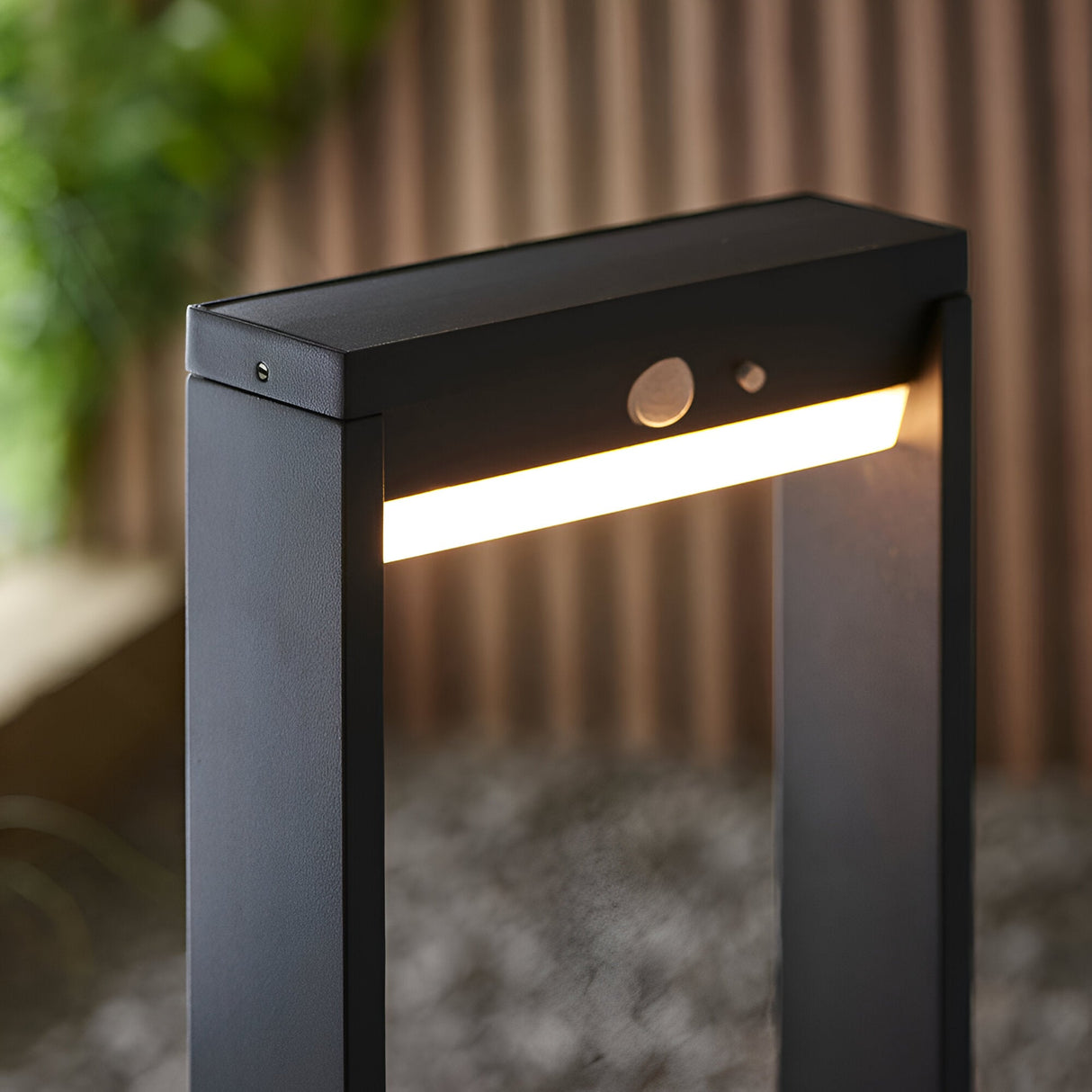 Close-up of the Endon Blythe LED solar post light in matte black aluminium, showing the warm white diffuser and PIR sensor on an outdoor path.