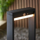 Close-up of the Endon Blythe LED solar post light in matte black aluminium, showing the warm white diffuser and PIR sensor on an outdoor path.