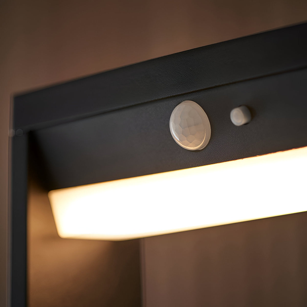 Close-up of the Endon Blythe LED solar post light in black aluminium, showing the PIR motion sensor and illuminated warm white diffuser.