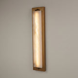 Valora vertical wall light with tall alabaster panel glowing warm white within a brushed brass rectangular frame, shown against a plain light background.