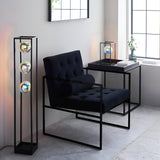 Brockwell Table Lamp in matt black open-frame design with iridescent orb glass shade, shown on a side table in a living room setting.