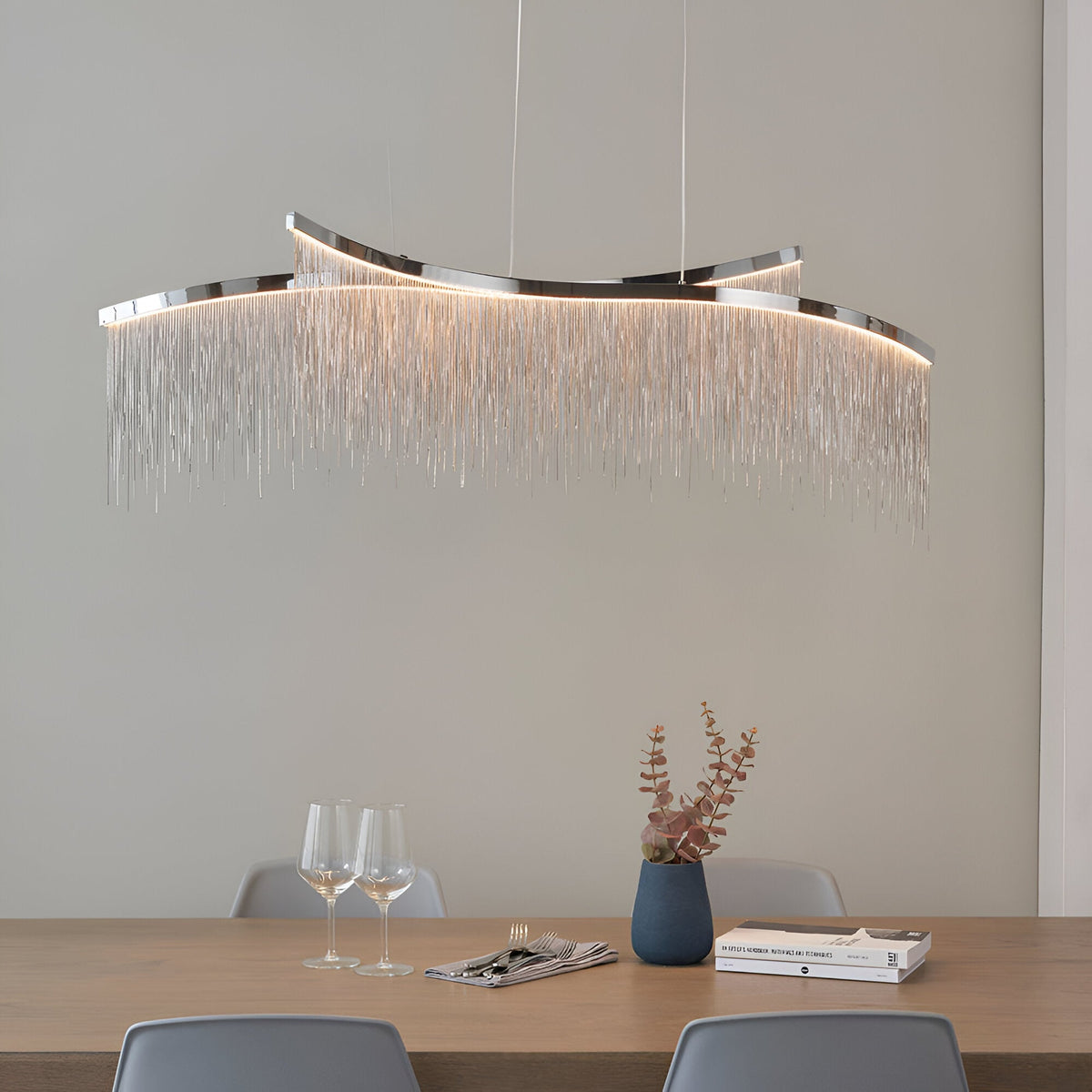 Endon Caststead linear pendant in polished chrome with cascading silver chain fringe and integrated LED, suspended above a wooden dining table.