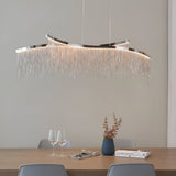 Endon Caststead linear pendant in polished chrome with cascading silver chain fringe and integrated LED, suspended above a wooden dining table.