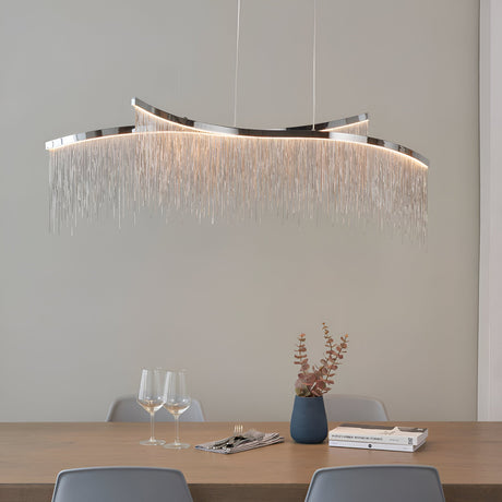 Endon Caststead linear pendant in polished chrome with cascading silver chain fringe and integrated LED, suspended above a wooden dining table.