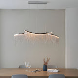 Endon Caststead linear pendant in polished chrome with cascading silver chain fringe and integrated LED, suspended above a wooden dining table.