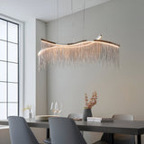 Endon Caststead linear pendant in polished chrome with a wavy bar and cascading silver chain fringe, suspended above a dining table with grey chairs.