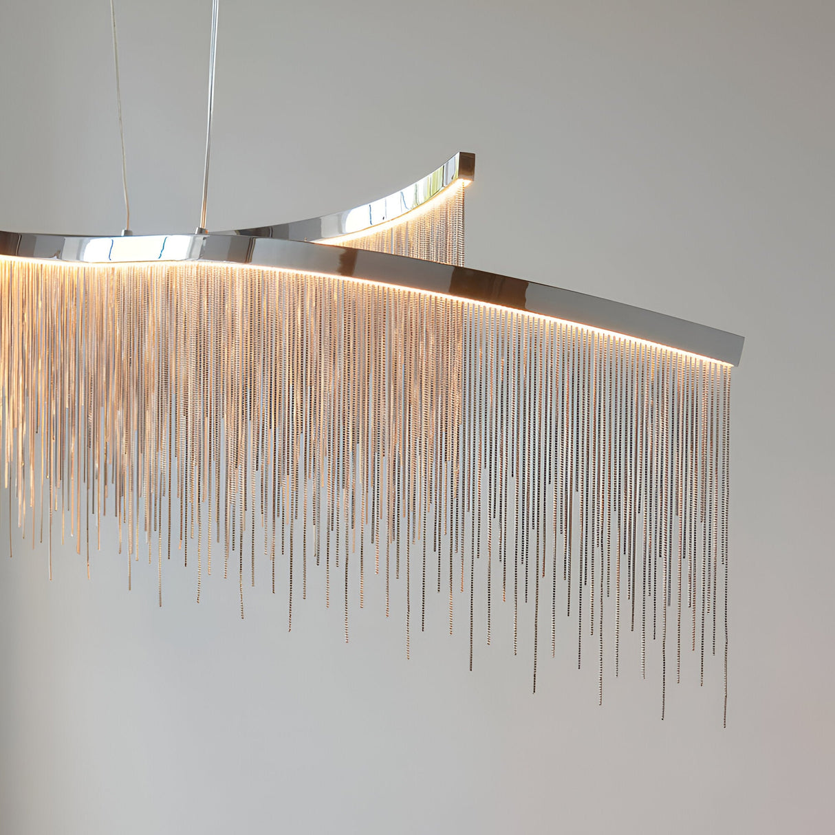 Endon Caststead Linear Pendant in polished chrome with a curved bar and cascading silver fringe chains illuminated by warm integrated LED light.
