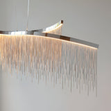 Endon Caststead Linear Pendant in polished chrome with a curved bar and cascading silver fringe chains illuminated by warm integrated LED light.