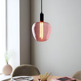 Pink-tinted E27 LED filament bulb glowing warm white inside a pink glass pendant light shade, in a dining room setting.