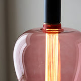 Close-up of a 2.8W E27 LED filament bulb with pink tinted glass, glowing warm white filaments visible inside a pendant light fitting.