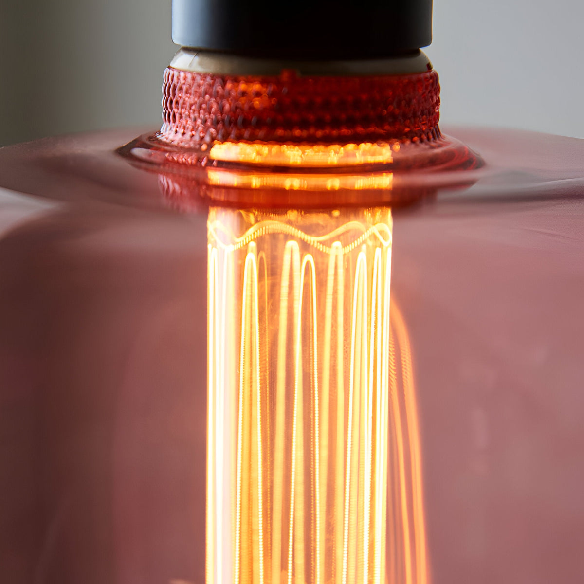 Close-up of the 2.8W E27 LED filament bulb showing pink tinted glass, visible warm white filaments, and a textured amber-red screw base.