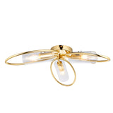Endon Hartley 3 light semi-flush ceiling light in brass with three clear glass cylinder shades on looped arms, shown on a white background.