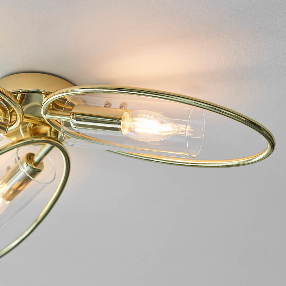 Close-up of Endon Hartley 3 Light Semi-Flush Ceiling Light in brass, showing an oval brass ring, clear glass shade and lit E14 candle lamp.