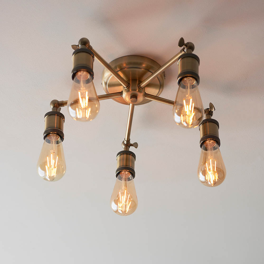 Brackley 5 Light Semi-Flush Ceiling Light in brass, five angled arms with exposed E27 filament bulbs, mounted close to a plain ceiling.