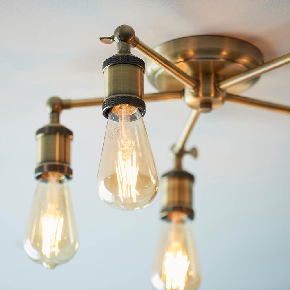 Brackley 5 Light Semi-Flush Ceiling Light in brass, close-up of exposed E27 bulbs on knurled holders and radiating metal arms against a white ceiling.